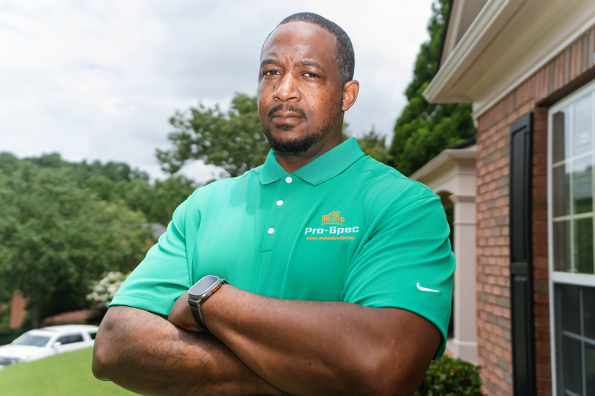 Lawrence Pruitt, founder of Pro-Spec, in a branded green polo outside a brick home